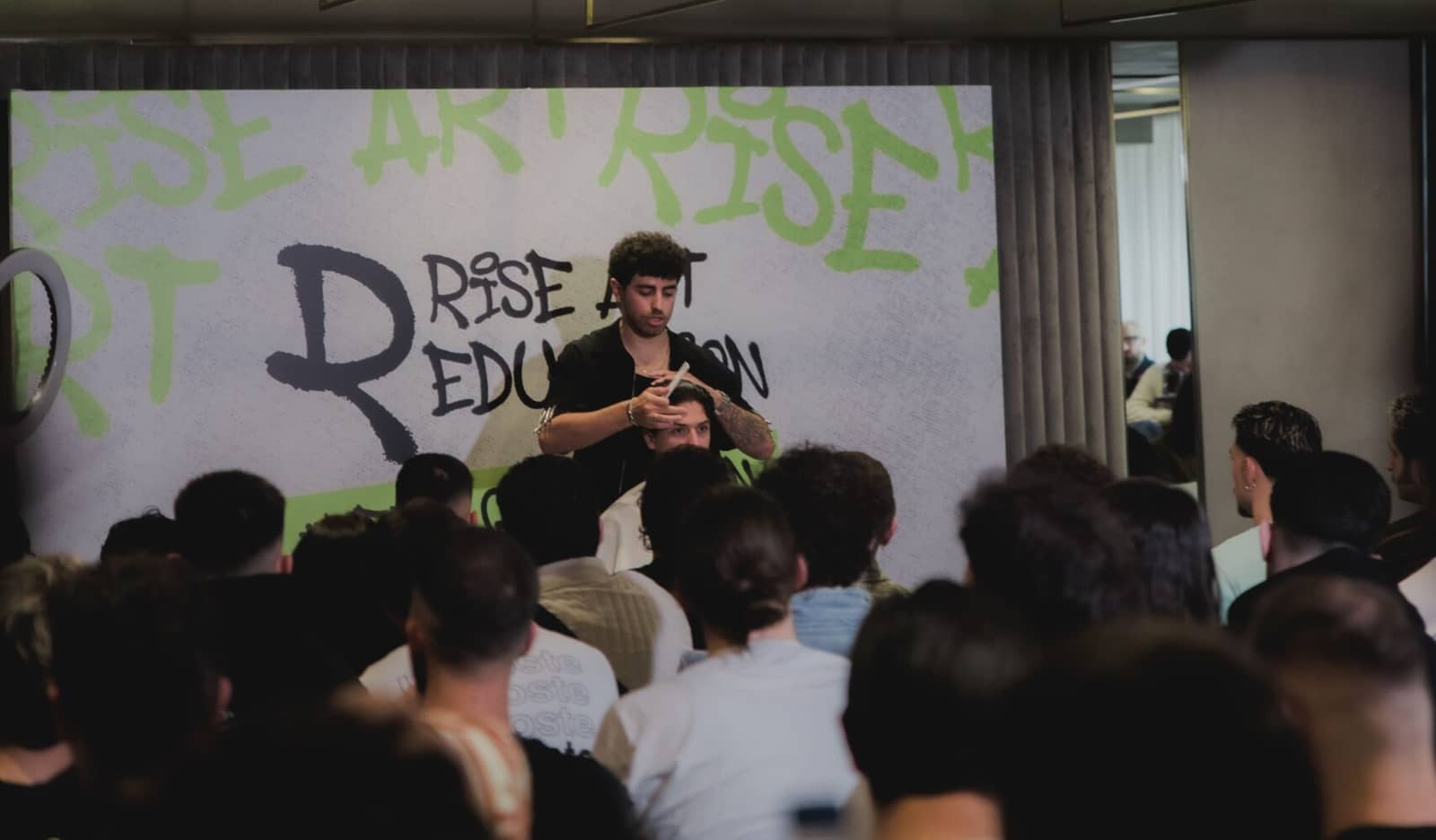 Σεμινάριο κουρέματος: ένας barber δουλεύει πάνω στη σκηνή και η αίθουσα παρακολουθεί
